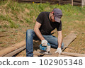 An adult man is engaged in carpentry work at a house construction site 102905348