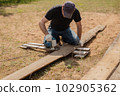 Man builds sections of fence around his yard out of planks 102905362