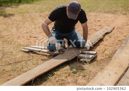 Man builds sections of fence around his yard out of planks Man builds sections of fence around his yard out of planks 102905362