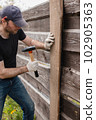 An adult man is engaged in carpentry work at a house construction site 102905363
