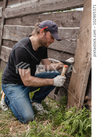 Man builds sections of fence around his yard out of planks Man builds sections of fence around his yard out of planks 102905371