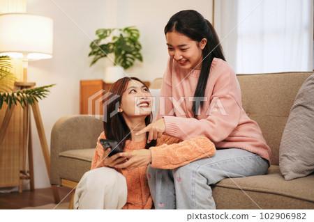 Young woman lesbian couple in sweater surfing social media on sm 102906982