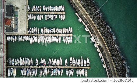 Aerial top down view of parked boats, motorboats and sailboats at marina piers 102907143