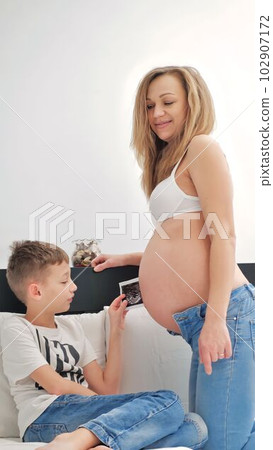 An interesting boy with a pregnant mother at home. embrace An interesting boy with a pregnant mother at home. embrace 102907172