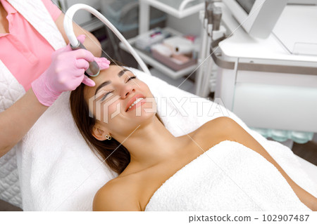 Skin therapy,cosmetic facial procedure,Anti-aging treatments. Beauty consultant is administering a cosmetic treatment on a young woman's face.dermatological service 102907487