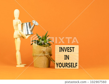 Invest in yourself symbol. Concept words Invest in yourself on wooden block on a beautiful orange table orange background. Businessman icon. Business and Invest in yourself concept. Copy space. 102907560