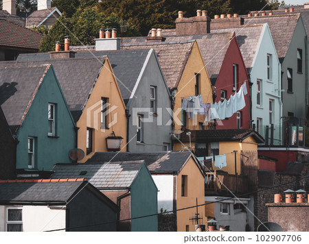 A row of colorful houses on the street of the Irish city of Cobh, urban landscape. Cozy European architecture. The laundry is dried on a clothesline. 102907706