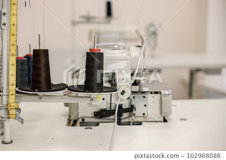 Cropped photo of black spools of thread on sewing machine 102908086