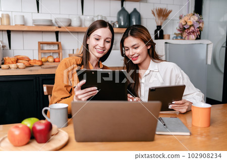 Two young woman reading business information in clipboard and di 102908234