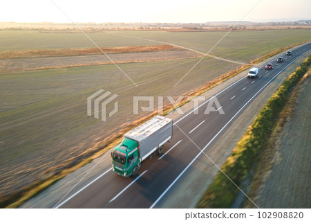 Aerial view of semi-truck with cargo trailer driving on highway hauling goods in evening. Delivery transportation and logistics concept 102908820