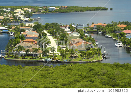 Aerial view of rural private houses in remote suburbs located near Florida wildlife wetlands with green vegetation on sea bay shore. Living close to nature concept 102908823