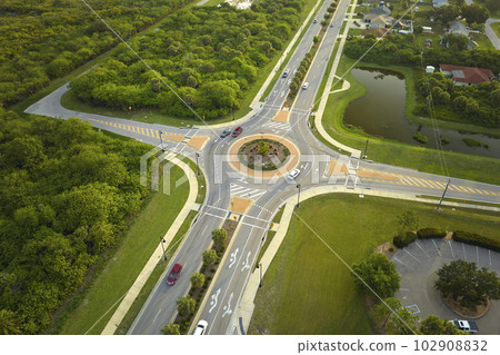 Aerial view of road roundabout intersection with moving cars traffic. Rural circular transportation crossroads Aerial view of road roundabout intersection with moving cars traffic. Rural circular transportation crossroads 102908832