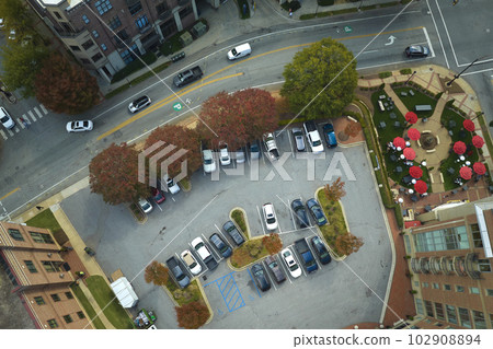 Aerial view of many colorful cars parked on parking lot on apartment building backyard. Place for vehicles in front of residential condo 102908894