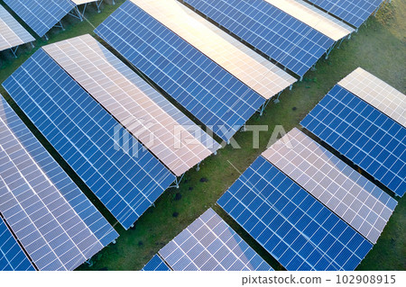 Aerial view of large sustainable electrical power plant with rows of solar photovoltaic panels for producing clean ecological electric energy. Renewable electricity with zero emission concept. Aerial view of large sustainable electrical power plant with rows of solar photovoltaic panels for producing clean ecological electric energy. Renewable electricity with zero emission concept. 102908915