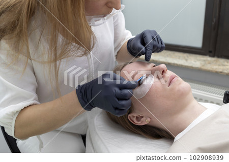 Beautician Applies Lash Lift Lotion On Rolled Hair During Eyelash Lamination Treatment Procedure In Beauty Salon. Curling, Staining, Extension Procedures For Lashes. Horizontal Plane. Step By Step 102908939