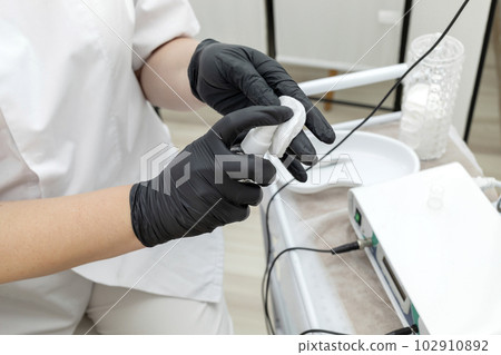 Cropped Electrologist Disinfects Client's Skin Before Hair Removal Procedure With Medical Electrolysis Device In Beauty Salon. Horizontal Plane. Hair Removal Treatment. Cropped Electrologist Disinfects Client's Skin Before Hair Removal Procedure With Medical Electrolysis Device In Beauty Salon. Horizontal Plane. Hair Removal Treatment. 102910892