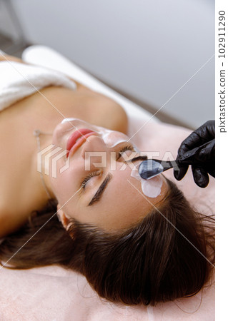 Facial treatment, Facial pampering, Cosmetic procedure, Skin purificatio, Skin scrubbing, Beauty Regimens, Dermatology Services, lifting procedure. The cosmetologist applies cream to the face of a 102911290