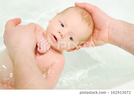 A young father bathes his newborn baby. Parenthood. A young father bathes his newborn baby. Parenthood. 102913072