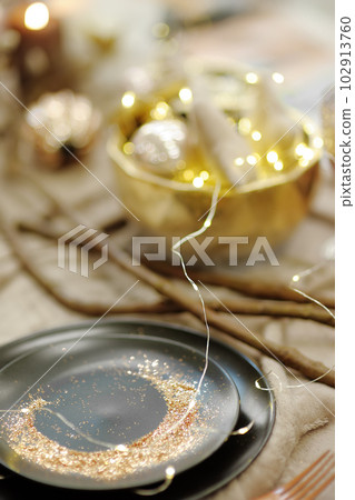 Stylish table set with black crockery, golden sand and original lights for wedding reception. Trendy wedding party 102913760