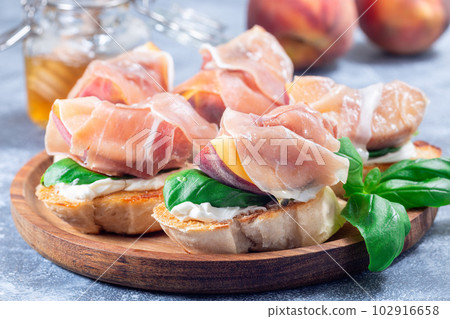 Prosciutto peach bruschetta on wooden plate, horizontal, closeup 102916658