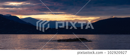 Rocky Island with Mountain Landscape in Background. Dramatic Sunset. 102920927