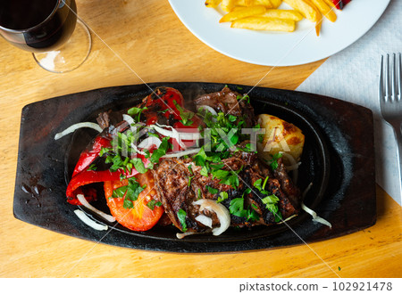 Baked pieces of beef with potato and vegetables in wooden plate Baked pieces of beef with potato and vegetables in wooden plate 102921478