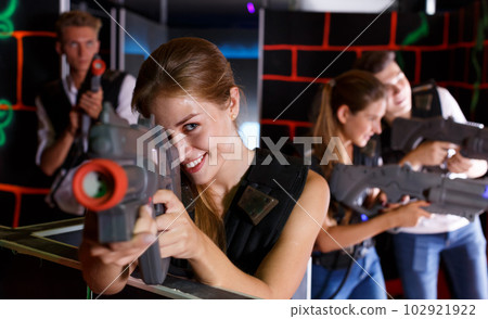 Girl holding laser pistol while playing lasertag game with her friends 102921922