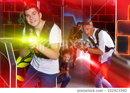 men and women playing emotionally laser tag game in arena men and women playing emotionally laser tag game in arena 102921992