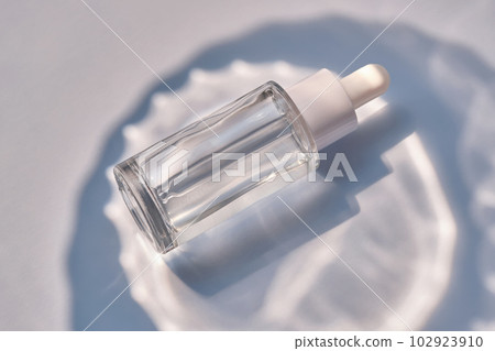 Serum bottle on a blue background with glare. Serum bottle on a blue background with glare. 102923910