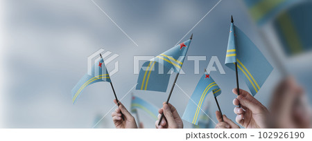A group of people holding small flags of the Aruba in their hands 102926190