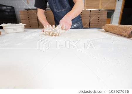Dough for pizza, the chef rolls out the blanks. Closeup hand of chef baker in uniform white apron cook pizza at kitchen 102927626