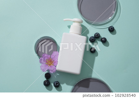 Unbranded pump bottle dispenser decorated with some glass petri dishes of purple liquid and purple flower. Blueberry (Vaccinium Corymbosum) extract helps treat and clear out acne and blemishes 102928540