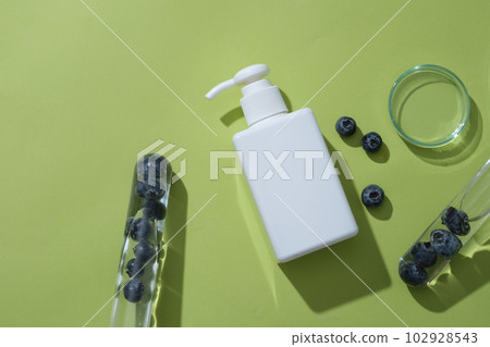 Test tubes containing blueberries inside, arranged with glass petri dish and unlabeled pump bottle. Blueberry help exfoliate dead skin cells thanks to high levels of salicylic acid present in it 102928543