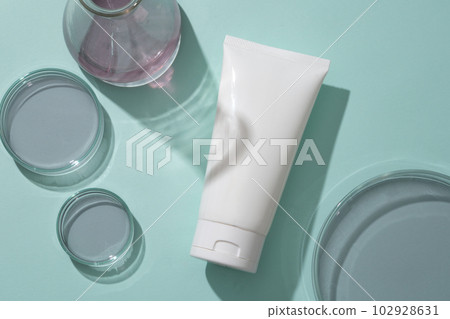 Flat lay of unlabeled cosmetic plastic bottle on blue background with lab glassware containing blueberry essence. Mockup for cosmetic from blueberry ingredient. Flat lay of unlabeled cosmetic plastic bottle on blue background with lab glassware containing blueberry essence. Mockup for cosmetic from blueberry ingredient. 102928631