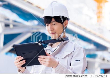 Business man in work clothes looking at tablet at construction site Business man in work clothes looking at tablet at construction site 102929251