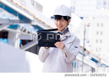 穿著工作服的商人在建築工地看平板電腦 穿著工作服的商人在建築工地看平板電腦 102929252