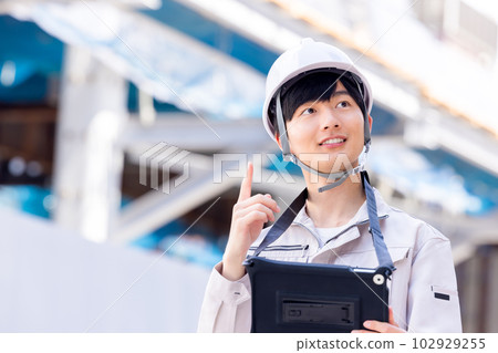 Business man in work clothes looking at tablet at construction site 102929255