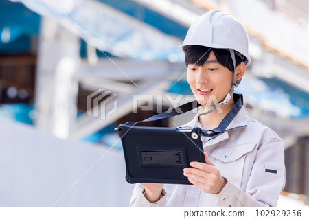 Business man in work clothes looking at tablet at construction site 102929256
