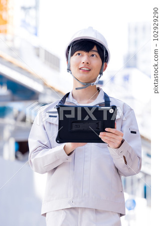 Business man in work clothes looking at tablet at construction site 102929290