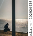 A woman sitting by the shining sea 102929436