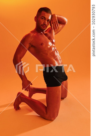 Man bodybuilder boxer muscle workout with naked torso with abs posing in studio. Advertising, sports, active lifestyle, colored yellow light, competition, challenge concept. Man bodybuilder boxer muscle workout with naked torso with abs posing in studio. Advertising, sports, active lifestyle, colored yellow light, competition, challenge concept. 102930793