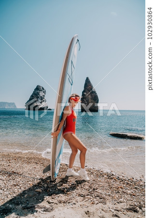 Woman sea sup. Close up portrait of happy young caucasian woman with blond hair looking at camera and smiling. Cute woman portrait in red bikini posing on sup board in the sea 102930864