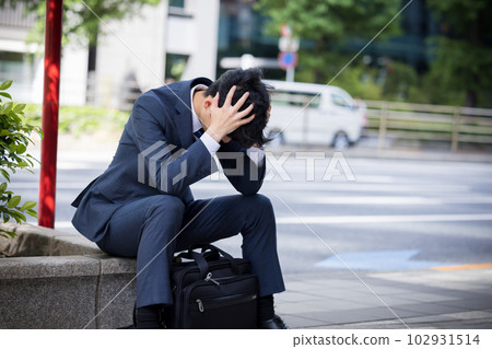 Business Businessman depressed and sitting on the roadside 102931514
