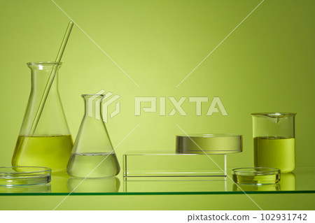 Round podium stacked on rectangular podium and decorated with laboratory glassware over pastel background. Cosmetic laboratory research and development 102931742