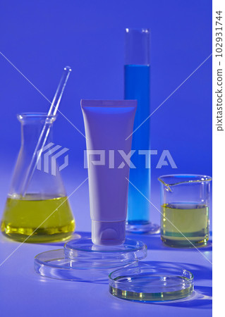 Laboratory filled with blue and yellow fluid decorated with a white tube standing on round podium. Mockup of skin care cosmetic tube of beauty facial Laboratory filled with blue and yellow fluid decorated with a white tube standing on round podium. Mockup of skin care cosmetic tube of beauty facial 102931744