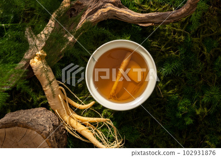 A bowl of tonic water from ginseng root on forest background, moss, leaves and dried twigs. Scene for advertising product of ginseng extract with natural concept. 102931876