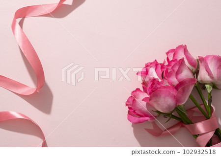 Beautiful roses displayed on pink background with pink soft ribbon. Space for cosmetic product presentation. Romantic composition for design cards and banner 102932518