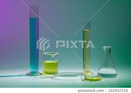 Abstract background with laboratory concept - lab glassware containing color liquid and round transparent podium for cosmetic product presentation on color background. 102932520