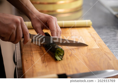 Chef cutting maki sushi rolls with cucumber Chef cutting maki sushi rolls with cucumber 102933769