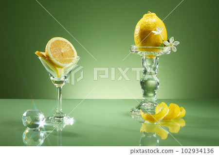 Luxury concept for advertising product from lemon ingredient. Slices and peel of lemon decorated on green background with glass cup crystal ball. Copy space 102934136
